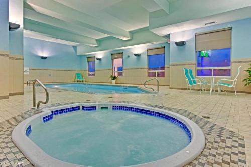 埃德蒙顿南埃德蒙顿智选假日套房酒店的酒店客房的大型游泳池配有椅子