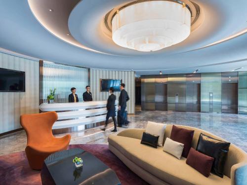 大园区台北诺富特华航桃园机场饭店的带沙发的大堂,有人站在房间里