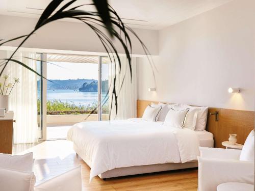 科梅诺Corfu Imperial, Grecotel Beach Luxe Resort的卧室设有白色的床和大窗户