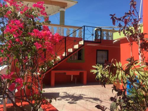 巴拉奥纳省圣克鲁斯La hermosa hotel的一座红色的建筑,有楼梯和粉红色的花朵