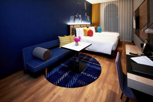 大阪Citadines Namba Osaka的酒店客房配有蓝色的沙发和床。