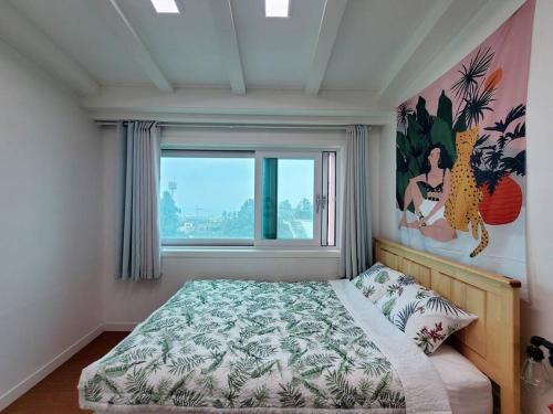 济州市Aewol Gwangryeong House的一间卧室设有一张床和一个大窗户