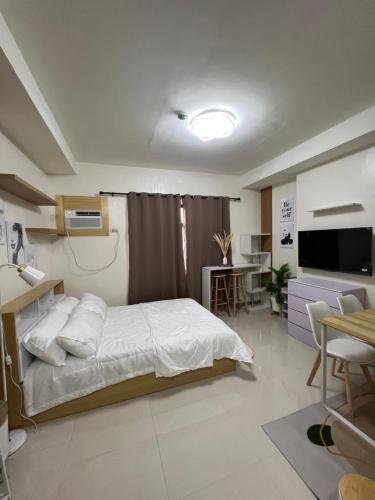 宿务Kristinas Homestay- Cozy Resort Vibe Condotel的一间卧室配有一张床、一张桌子和一台电视