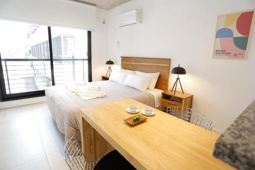 布宜诺斯艾利斯OWN Belgrano Studios & Suites的一间卧室配有一张床和一张木桌
