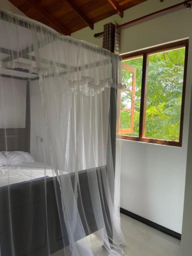 坦加拉Dinuri villa的一间卧室设有天蓬床和窗户。