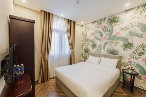 富国Tropical Bay Grand World Phu Quoc的卧室配有白色的床和花卉墙