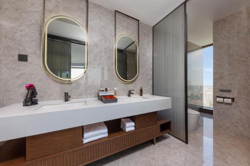 佛山佛山王府井紫薇港逸扉酒店的浴室设有2个水槽和2面镜子