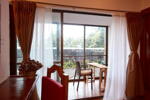 博卡拉Brookside Villa Pokhara的客厅设有大窗户和桌椅