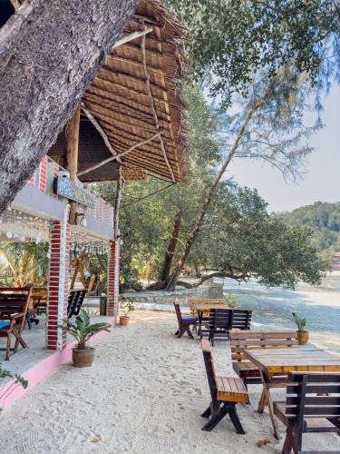 昌岛Full Moon Bungalow Resort Koh Chang Ranong的海滩上的一组长椅和桌子