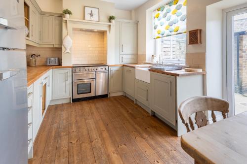 锡豪西斯Pebble Cottage的厨房铺有木地板,配有白色橱柜。