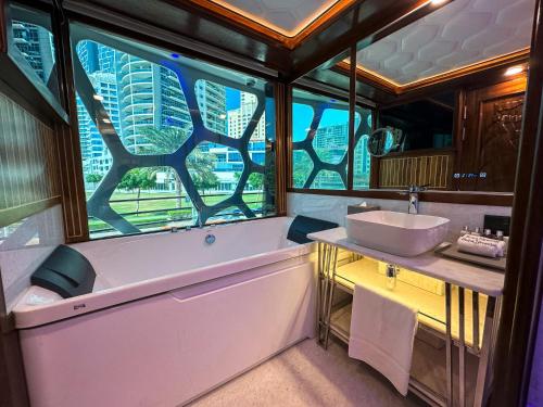 迪拜Overnight Super Yacht - Orchid的带浴缸、水槽和窗户的浴室