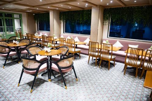 古瓦哈提Hotel SUI的餐厅设有木桌、椅子和窗户。