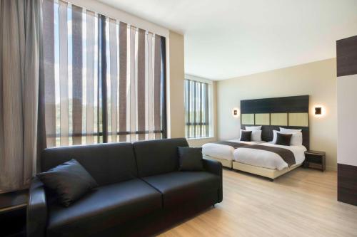 桑利斯Best Western Plus Hôtel Escapade Senlis的客厅配有一张床和一张沙发
