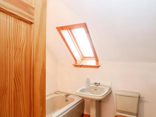 PaibleAr Dachaigh的一间带水槽和卫生间的浴室以及窗户。