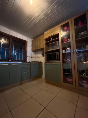 卡庞达卡诺阿Legítima casa de praia的一个带绿色橱柜和窗户的大厨房