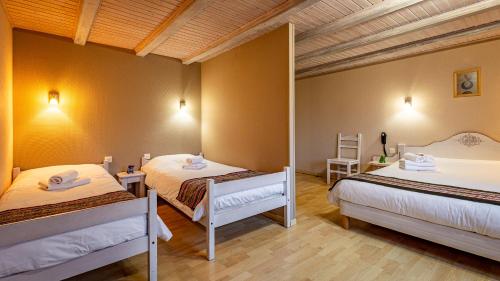 拉布雷斯Hôtel - Restaurant Le Couchetat的一间卧室设有两张床和木制天花板