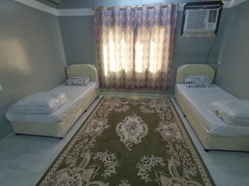 MisfāhAtiaf Jabal Shams house的配有地毯和窗户的客房内的两张床