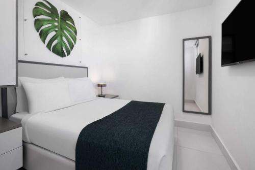 圣多明各GRAN HOTEL EUROPA TRADEMARK COLLECTION by WYNDHAM的白色的卧室配有白色的床和镜子