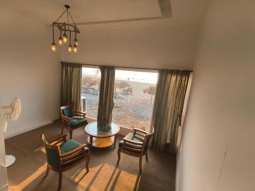 曼德姆Aqua Beach Resort Ashwem的客厅配有椅子、桌子和窗户