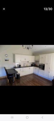 ClonardClonard Cottage的厨房配有白色橱柜和黑色桌子