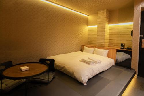周南市ピンポンホテル&キャビン pin pon hotel & cabin的小型酒店客房配有一张床和一张桌子