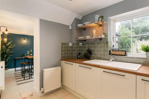 EnstoneStunning 3BD Oxfordshire Cottage in Enstone的厨房配有白色橱柜、水槽和窗户。