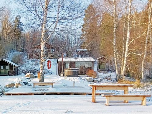 VihtiHoliday Home Hiidenlumo by Interhome的小屋前的雪地里放着两长椅