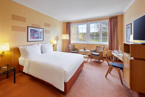 韦斯特尔堡Lindner Hotel Wiesensee的酒店客房设有一张白色大床和一张书桌