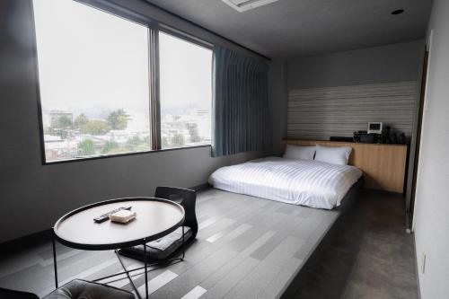 周南市ピンポンホテル&キャビン pin pon hotel & cabin的酒店客房配有一张床、一张桌子和一张桌子以及椅子。