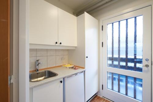 岑讷汽车公寓旅馆的厨房配有白色橱柜、水槽和窗户。