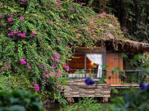 宁平Tam Coc Lion Kings Hotel & Resort的一座粉红色花朵长在里面的房子