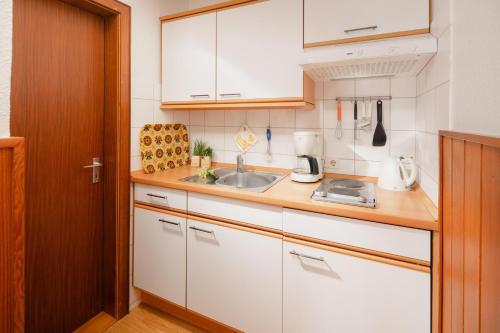 诺德奈Haus Meeresblick Wohnung 2的小厨房配有白色橱柜和水槽