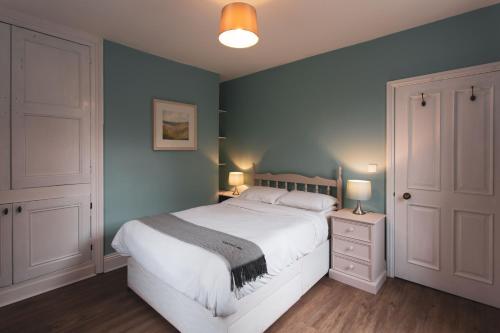 New MillsThe Fireman's House, Lowe's Mill Cottages at Torr Vale Mill的一间卧室设有一张大床和蓝色的墙壁