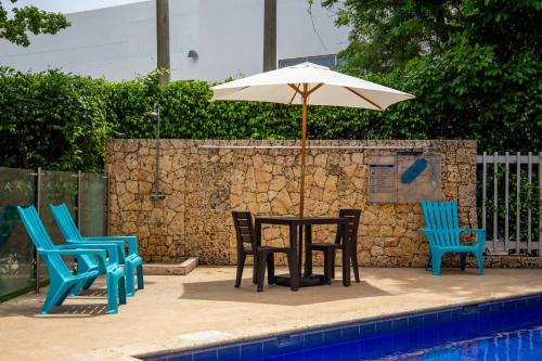 卡塔赫纳HOTEL OCEANIA的游泳池旁配有遮阳伞的桌椅
