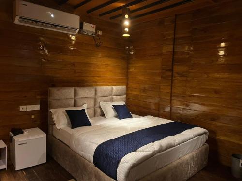 北拉欣布尔Lemonwood cottage的一间卧室配有一张带木墙的大床