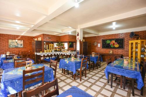 卡内拉Hotel Pequenino的一间设有蓝色桌椅的餐厅,拥有砖墙