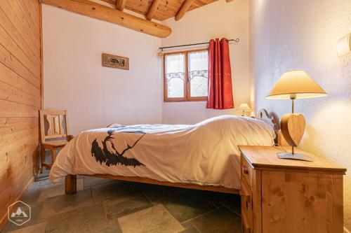 泰尔米尼翁"L'Ancolie" Appartement de Charme 4 Personnes à Val Cenis的一间卧室配有一张床和一张带台灯的桌子
