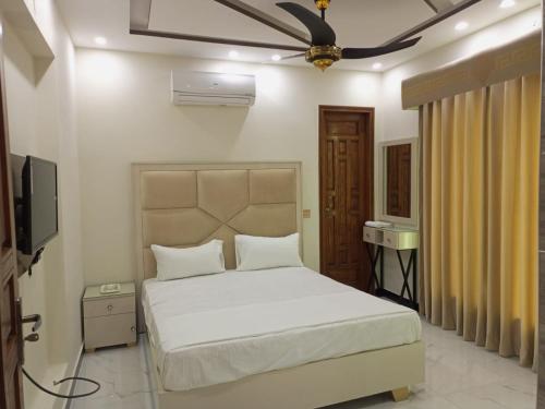 拉合尔Dove Inn Family Residency Johar Town的卧室配有白色的床和吊扇