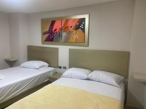 巴兰基亚HOTEL DASANTO HD的一间设有两张床的客房,墙上挂着一幅画