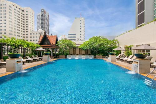 曼谷The Sukosol Hotel的一座带椅子和建筑的大型游泳池