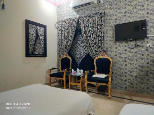 拉合尔Hotel Eden Plus Lahore的一间卧室配有两把椅子、一张桌子和一台电视。