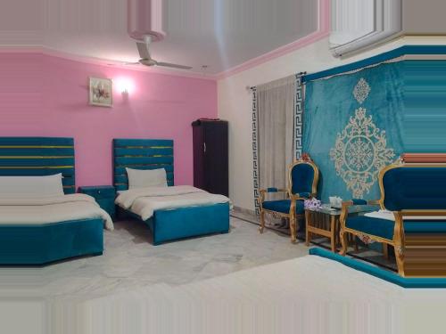 拉合尔Hotel Eden Plus Lahore的一间设有两张床和两把椅子的房间