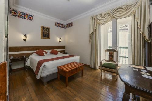 库斯科La Casona Real Cusco的卧室配有1张床、1张桌子和1把椅子
