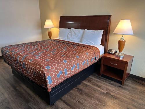 阿尔伯克基Desert Sands Inn & Suites的酒店客房设有一张床和一个带电话的床头柜