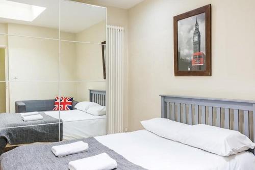 伦敦Spacious 3 bedrooms in Edgwar road的一间卧室配有两张床和镜子