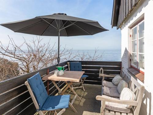 海斯勒Holiday Home Asgot - 15m from the sea in Bornholm by Interhome的阳台配有桌椅和遮阳伞