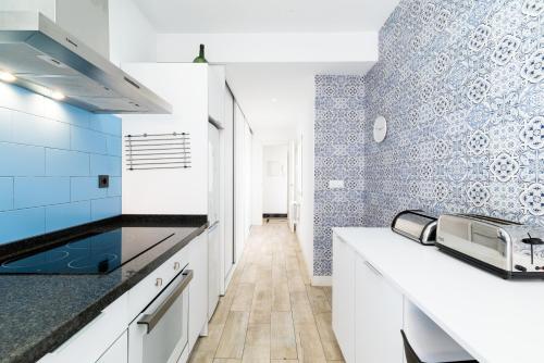 格拉纳达Neptuno Ático, con terraza的厨房配有白色橱柜和蓝色瓷砖