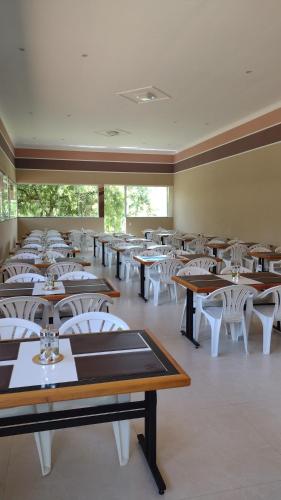 阿瓜斯迪林多亚Pousada Vida feliz的一间配有桌子和白色椅子的用餐室