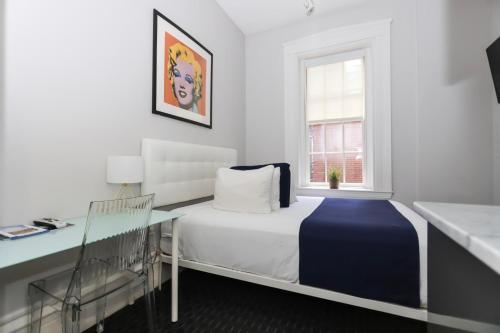 波士顿Charming & Stylish Studio on Beacon Hill #2的一间卧室配有一张床、一张书桌和一个窗户。