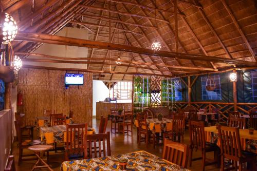 GuluAfrican Roots Gulu的一间带桌椅和电视的用餐室